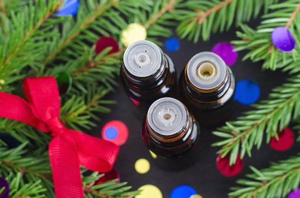 Tre bottiglie di olio essenziale e rami di abete. Aromaterapia natalizia e concetto di spa . — Foto Stock