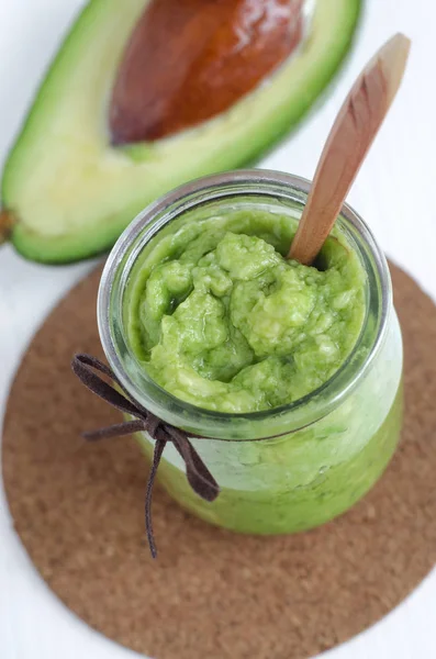 Homemade avocado mask in a glass jar. Prepared from mashed avocado and olive oil. Diy cosmetics. — Stock Photo, Image