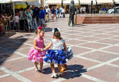 RONDA, ANDALUSIA/SPAIN - SEPTEMBER 10: Three little girls in traditional spanish dress dancing in the square. The local holiday of La Feria de Pedro Romero. Ronda, Spain on September 10, 2016 clipart