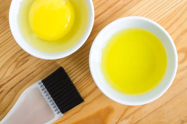 Minyak zaitun dan telur mentah dalam mangkuk keramik kecil untuk mempersiapkan spa buatan sendiri dan masker rambut. Bahan untuk kosmetik diy . — Stok Foto