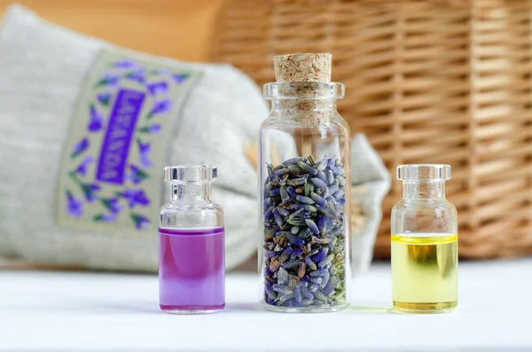 Three small bottles with dry lavender buds, essential oil and natural perfume. Aromatherapy and spa ingredients. — Stock Photo, Image