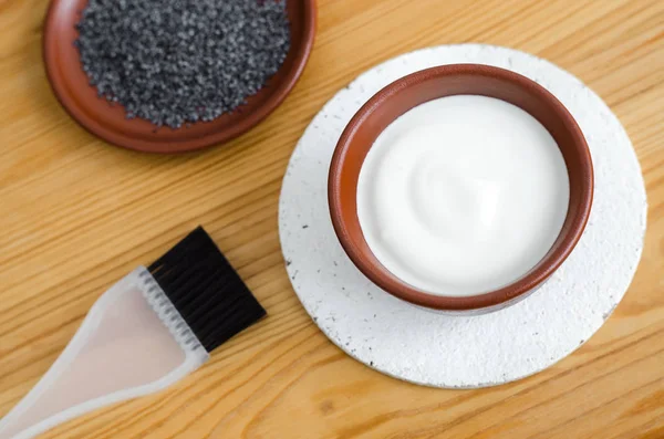 Small ceramic bowl with sour cream (greek yogurt) and poppy seeds. Ingredients for preparing facial mask or scrub. Homemade cosmetics — Stock Photo, Image