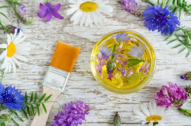 Aroma çiçekler ile Kozmetik yağı ile küçük cam kase ayıklar. Doğal kozmetik maddeler. Organik cilt bakımı, ev yapımı kozmetik ve spa konsept. 