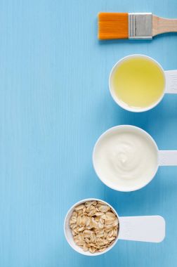 Ekşi krema (ya da Yunan yoğurt), koptu yulaf ve zeytin yağı küçük bir plastik kaşık toz - DIY maske, önlük ve nemlendiriciler hazırlanması için malzemeler. Ev yapımı kozmetik. Üstten Görünüm, kopya alanı. 