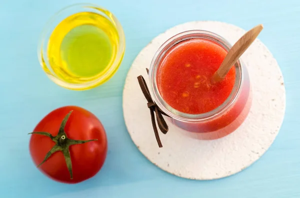 Tomato puree in a glass jar and olive oil for preparing homemade face and hair mask. Ingredients of DIY cosmetics.