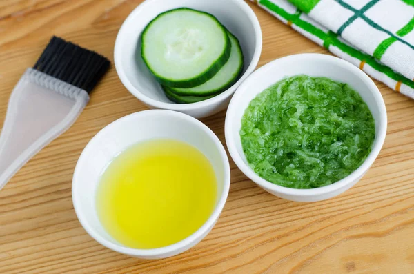 Pepino y aceite de oliva en pequeños cuencos de cerámica blanca para preparar mascarilla facial natural. Receta de cosméticos caseros — Foto de Stock