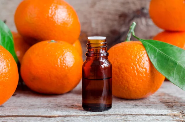 Small bottles with orange mandarin essential oil (tangerine extract, tincture, infusion, perfume). Aromatherapy, spa and herbal medicine ingredients. Old wooden background. Copy space — Stock Photo, Image