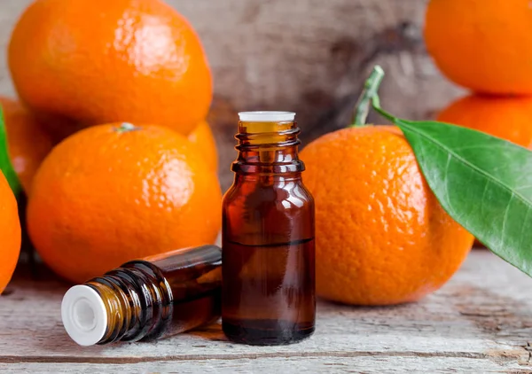 Two small bottles with sweet orange essential oil (extract, tincture, infusion, perfume). Aromatherapy, spa and herbal medicine ingredients. Old wooden background. Copy space