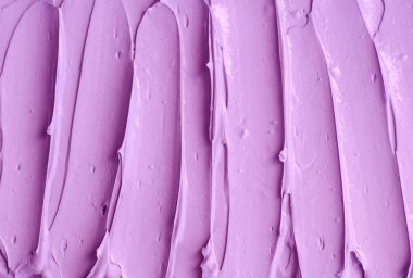 Mor yüz kremi (yüz maskesi, vücut sargısı, saç kremi) dokusu yakın, seçici odaklanma. Fırça darbeleriyle lavanta soyut arkaplan.    