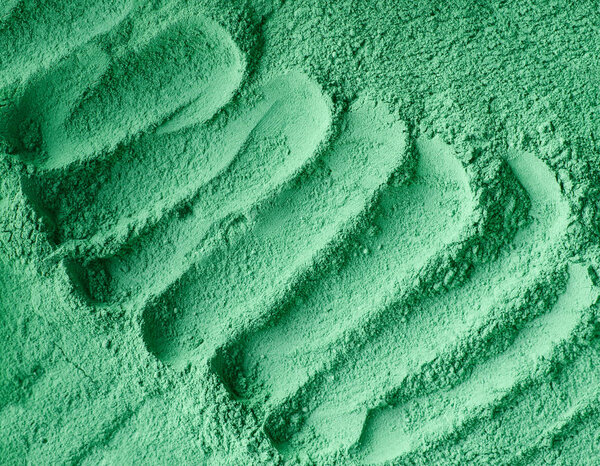 Green cosmetic clay powder (facial mask, face cream, body wrap) texture close up, selective focus. Abstract background with brush strokes