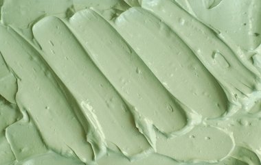 Yeşil kozmetik kil (salatalık yüz maskesi, avokado yüz kremi, vücut ambalajı) dokusu yakın, seçici odaklanma. Fırça darbeleriyle soyut arkaplan