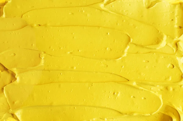 Yellow cosmetic facial mask (cream, body scrub) texture close up, selective focus. Abstract background with brush strokes.