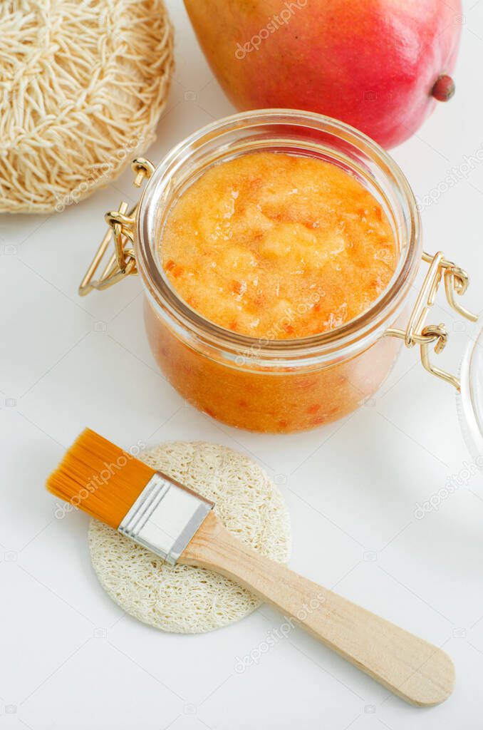 Homemade mango facial mask (exfoliating sugar face and body scrub) in the glass jar. Fruit DIY beauty treatment and spa recipe. Top view, copy space 