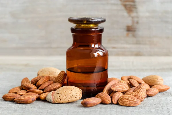 Botella de farmacia con aceite de almendras. Antiguo fondo de madera. Almendras cerca. Copiar espacio — Foto de Stock