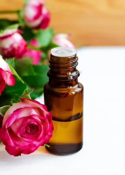 Frasco de vidro pequeno com óleo essencial de rosa. Aromaterapia, spa e ingredientes de ervas medicinais. Espaço de cópia . — Fotografia de Stock