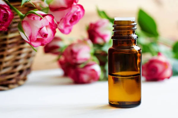 Malá skleněná lahvička s esenciálním růžovým olejem. Aromaterapie, lázeňské a bylinné léčivé složky. Kopírovat prostor. — Stock fotografie