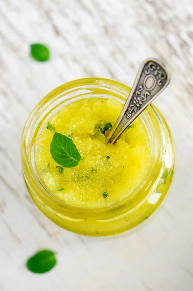 Homemade exfoliating scrub for face and body with sugar, honey, lemon, olive oil and mint. DIY cosmetics and spa recipe.