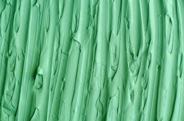 Yeşil kozmetik kil (yüz maskesi, yüz kremi, vücut ambalajı) dokusu yakın, seçici odaklanma. Fırça darbeleriyle soyut arkaplan. 