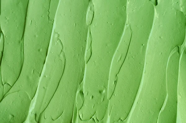 Zielona glina kosmetyczna (maska ogórkowa, krem do twarzy z awokado, okłady z zielonej herbaty) tekstura zbliżenie, selektywne skupienie. Streszczenie tła z pociągnięciami pędzla — Zdjęcie stockowe