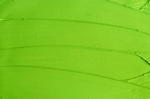 Green cosmetic clay (matcha facial mask, green tea and lime face cream, body wrap) texture close up, selective focus. Abstract background with brush strokes