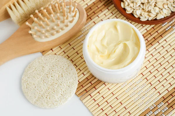 Yellow facial mask (banana face cream, shea butter hair mask or body butter) in the small white jar. Natural skin and hair care concept.