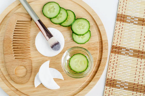 Cucumber water, cucumber slices, cotton pads, handmade cotton eye patches, cosmetic brush, wooden hair comb. Ingredients for preparing homemade mask. Natural beauty treatment recipe and zero waste