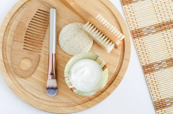 Fresh greek yogurt, make-up brush, loofah sponge, wooden hair comb and body brush. Ingredients for preparing homemade mask. Natural skin care recipe and zero waste concept. Top view, copy space