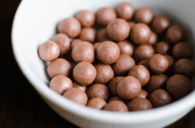 Beyaz bir kasede bronzlaştırıcı mineral incileri. Sağlıklı cilt tonu için bronz toplar. Yaklaş, seçici odaklanma 