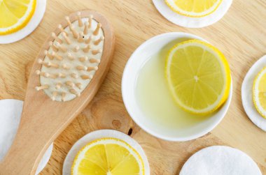 Limon suyu, limon dilimleri ve ahşap saç fırçası. Ev yapımı saç maskesi ya da yüz toneri hazırlamak için gerekli malzemeler. Doğal güzellik tedavi tarifi ve sıfır atık konsepti. Üst görünüm, alanı kopyala. 