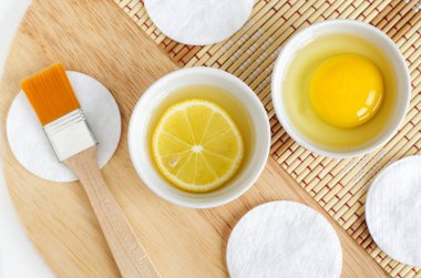 Limon suyu, limon dilimi ve küçük beyaz kaselerde çiğ yumurta. Doğal ev yapımı saç tedavisi ve sıfır atık konsepti. Üst görünüm, alanı kopyala