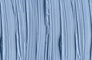 Açık mavi bentonit yüz kilini (maske, yüz kremi, vücut sargısı) kapat, seçici odaklanma. Fırça darbeleriyle soyut arkaplan.