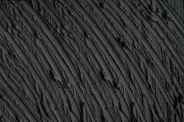 Black cosmetic clay (charcoal facial mask, cream, body wrap) texture close up. Abstract background with brush strokes. Selective focus.