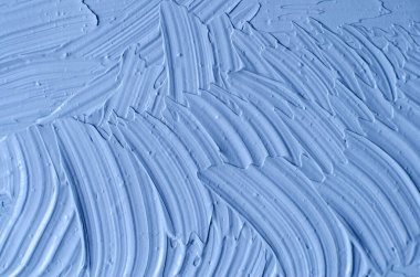 Açık mavi bentonit yüz kilini (aljinat maskesi, yüz kremi, vücut sargısı) kapat, seçici odaklanma. Fırça darbeleriyle soyut arkaplan. 