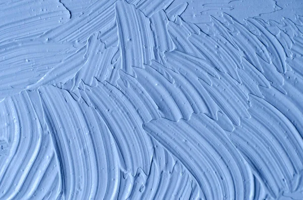 Açık mavi bentonit yüz kilini (aljinat maskesi, yüz kremi, vücut sargısı) kapat, seçici odaklanma. Fırça darbeleriyle soyut arkaplan. 