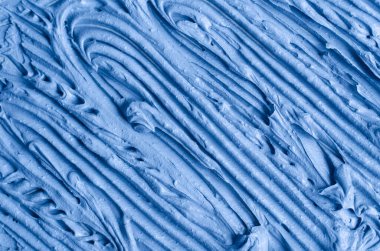 Açık mavi bentonit yüz kilini (aljinat maskesi, yüz kremi, vücut sargısı) kapat, seçici odaklanma. Fırça darbeleriyle soyut arkaplan. 