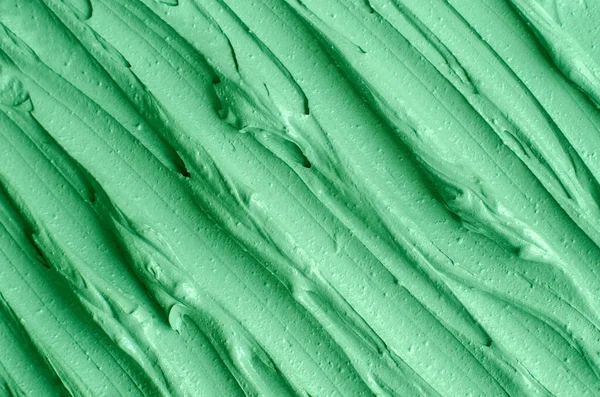 Green cosmetic clay (kelp facial mask, face cream, spirulina body wrap) texture close up, selective focus. Abstract background with brush strokes.