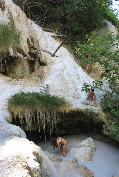Два человека купаются в природном бассейне с горячими источниками Баньи-Сан-Филиппо — стоковое фото