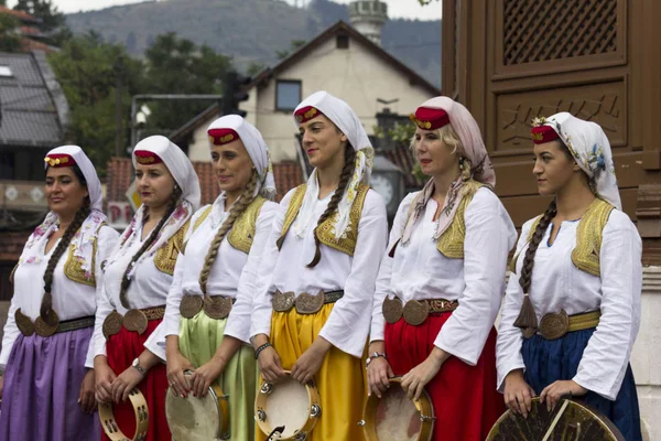 Tefleri tutan Geleneksel giyimli Bosnalı kızların önünde Sebilj çeşme, Sarajevo, Bosna Hersek - 20 Ağustos 2017: Grup