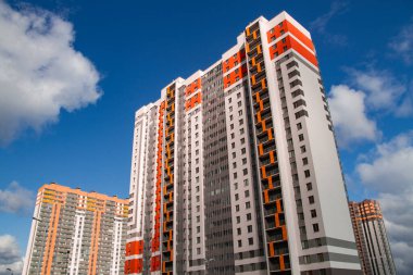 Mavi gökyüzüne karşı inşa edilmiş yeni gökdelenlerin ön cephesi. Tipik bir yerleşim yeri inşa etme kavramı