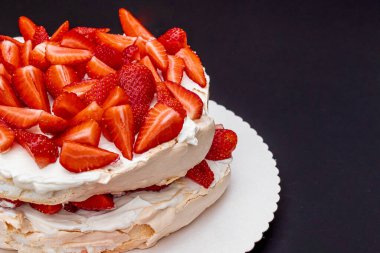 Ev yapımı Pavlova tatlısı. Siyah arka planda taze organik çilek ve metin için yer var. Bahar tatlısı. Yaz tatlısı. Ev yemeği konsepti. Tatlıyı kapat..