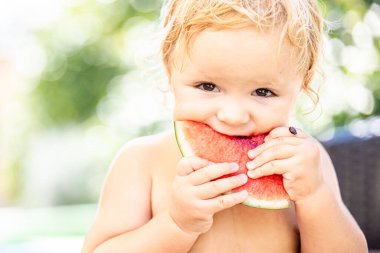 Bebek su ısırıyor. Erilonlu. Karpuz yiyen çocuk. Bahçede karpuz yiyen sevimli, beyaz ırklı, beyaz bir çocuğun yaşam tarzı portresi. Yaz kavramı. Mutlu bir çocukluk. Tatil havası.
