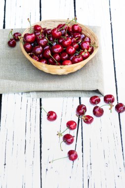 Kiraz. Taze kirazlar ve yeşil yapraklar dokuma kabında beyaz kırsal arka planda mesaj için boş alan. Bahar geldi. Yaz tatili. Sağlıklı çerez