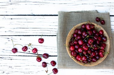 Kiraz. Taze kirazlar ve yeşil yapraklar dokuma kabında beyaz kırsal arka planda mesaj için boş alan. Bahar geldi. Yaz tatili