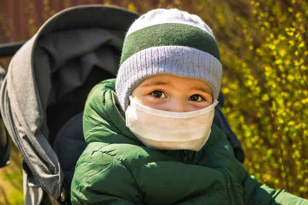 Koronavirüs salgını sırasında sokakta maske takan küçük bir çocuk.