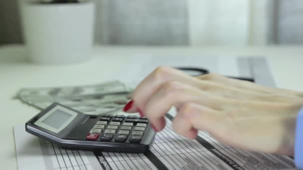 Femme utilise une calculatrice, écrit des calculs et éteint la calculatrice 