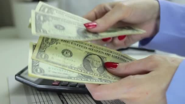 女性は、計算機、コイン、拡大鏡付きの机の背景に現金をカウントします。 — ストック動画