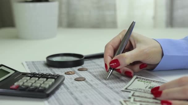 Mujer adulta joven hace correcciones a una tabla con datos sobre ingresos y gastos — Vídeos de Stock
