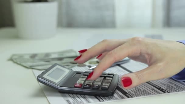 Femme utilise la calculatrice assis derrière un bureau avec de l'argent, loupe et stylo 