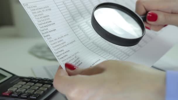 Mujer sentada en un escritorio con lupa examinando la mesa del presupuesto familiar — Vídeos de Stock