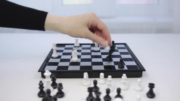 チェスの試合だ。白駒が黒の王に当たった。若い女性は勝利の動きを作る — ストック動画